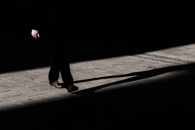 在灰色地板上有阴影的狭窄小路上行走的人
